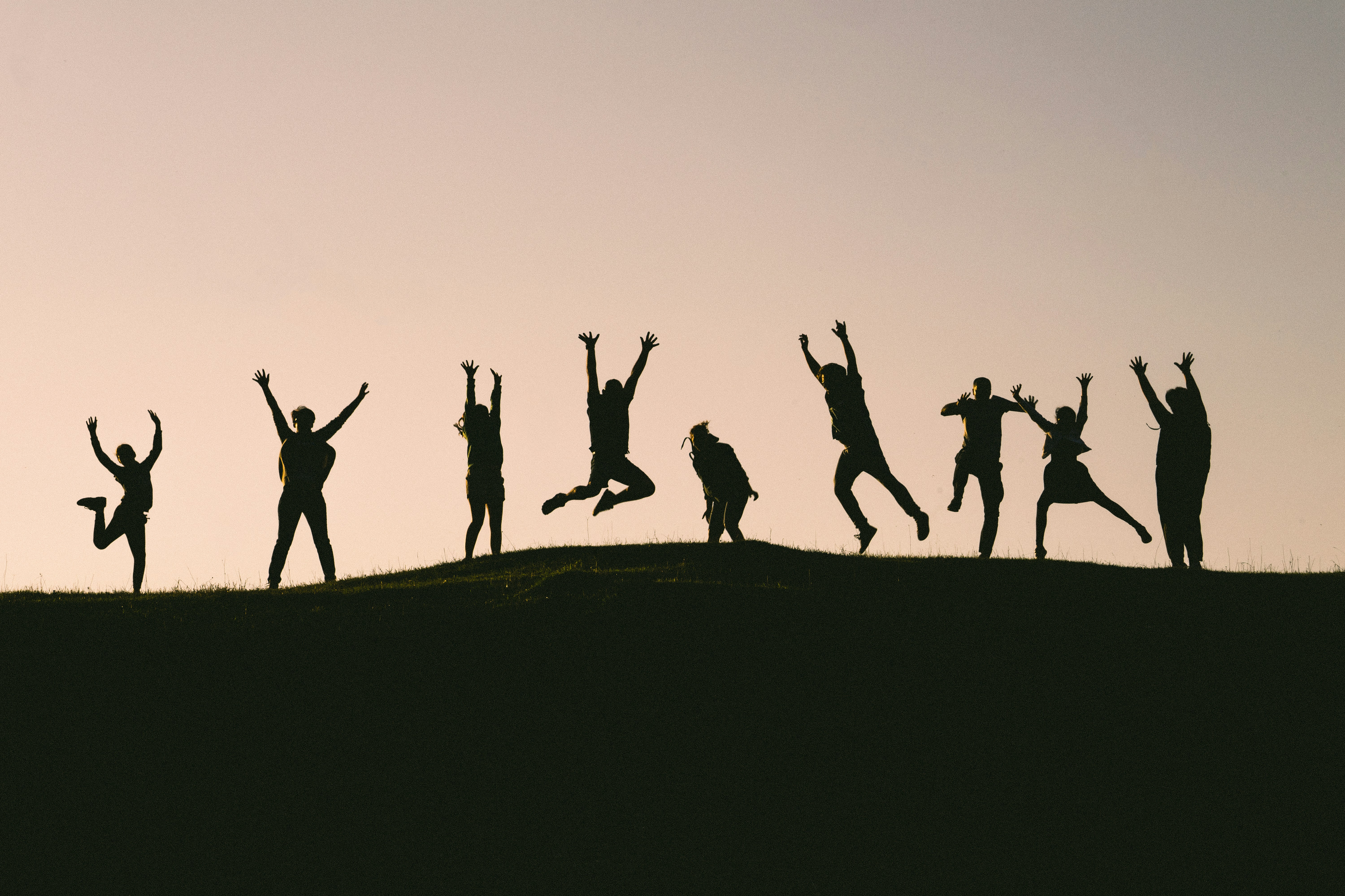 Group of people celebrating on a hilltop at sunset